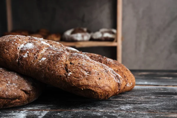 Pain avec farine sur table en bois foncé à la boulangerie — Photo