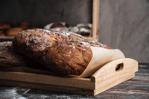 Pain avec farine sur table en bois foncé à la boulangerie — Photo