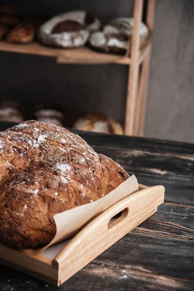 Pain avec farine sur table en bois foncé à la boulangerie — Photo