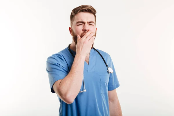 Portrait of a tired young medical doctor yawning isolated — Stock Photo, Image