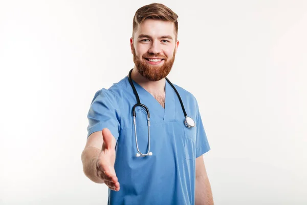 Retrato de um médico sorridente amigável esticando a mão para aperto de mão — Fotografia de Stock