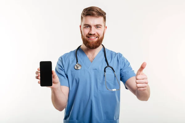 Doktor s telefonem ukazuje palec — Stock fotografie