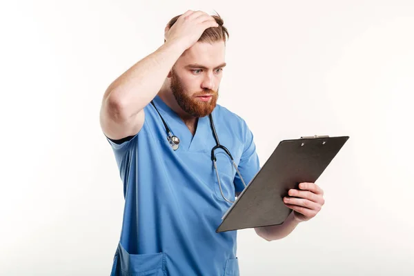 Zamyślony lekarz lub pielęgniarka z patrząc na Schowka stetoskop — Zdjęcie stockowe