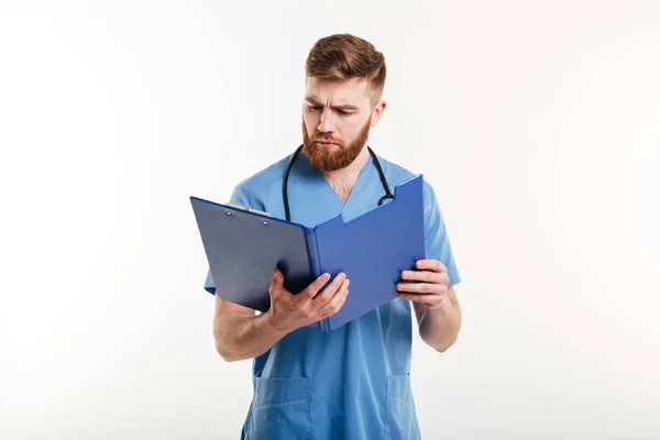 Pensive medical doctor or nurse with stethoscope looking at clipboard — Stock Photo, Image