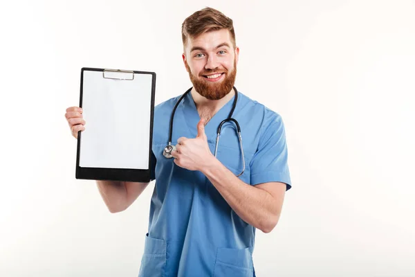 Selbstbewusster junger Arzt hält Klemmbrett und gibt Daumen hoch — Stockfoto