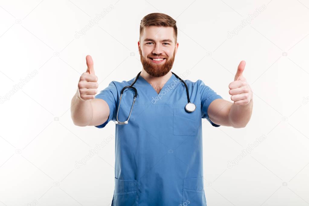 Portrait of a young friendly man doctor with stethoscope showing