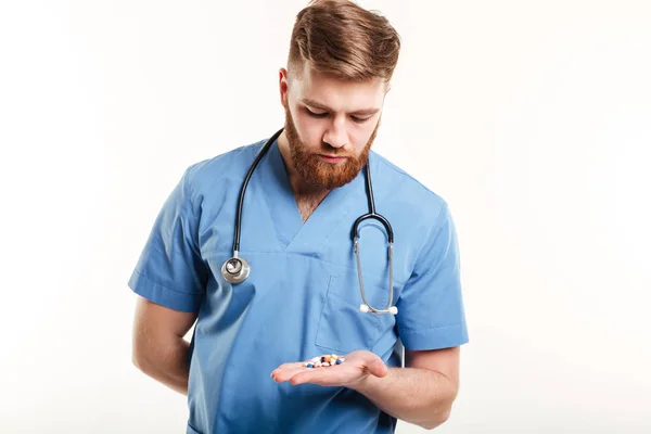 Médico ou enfermeiro com estetoscópio olhando para pílulas na palma da mão — Fotografia de Stock