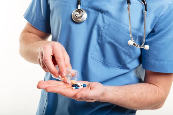 Mannelijke artsen gieten pillen froma een fles op zijn palm — Stockfoto