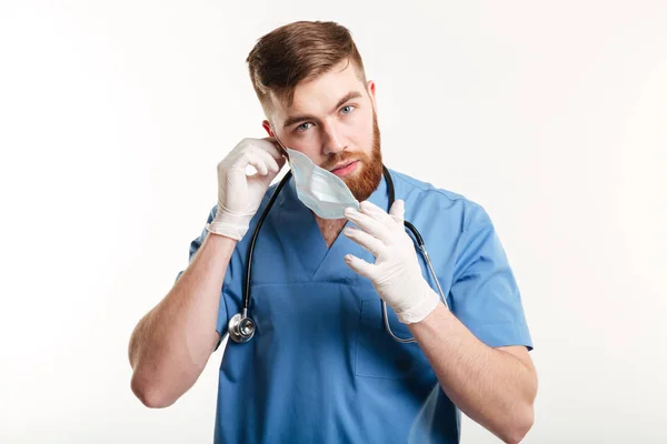 Assistente médico masculino com estetoscópio tirando a máscara — Fotografia de Stock