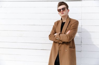 Kendine güvenen erkek güneş gözlüğü ve ceket silah ile ayakta geçti