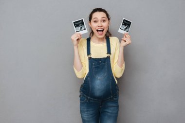 Happy pregnant woman holding ultrasound scans clipart