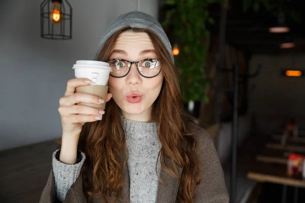 Sorprendido linda mujer joven sosteniendo la taza de café en la cafetería — Foto de Stock