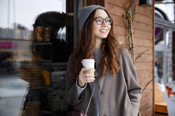 Sokakta yürüyen ve kahve içme neşeli sevimli genç kadın — Stok fotoğraf