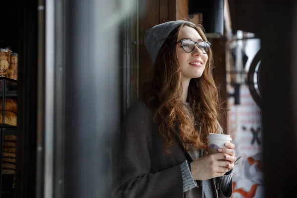 Feliz atraente jovem mulher pensando e bebendo café ao ar livre — Fotografia de Stock