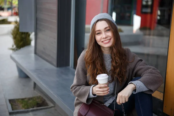 Mulher alegre sentado e bebendo café-to-go na cidade — Fotografia de Stock