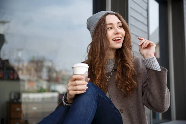 Vrolijke vrouw zitten en drinken koffie buiten in de stad — Stockfoto