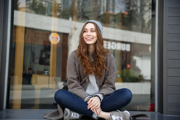 Jovem mulher atraente alegre sentado ao ar livre na cidade — Fotografia de Stock