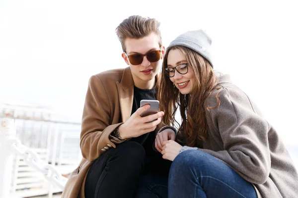 Casal usando telefone celular juntos na praia no outono — Fotografia de Stock