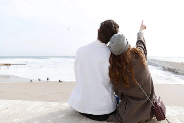 Vista trasera de la pareja sentada en la playa en otoño —  Fotos de Stock