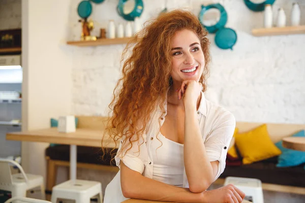 Mooie roodharige jonge dame zitten in Cafe terwijl poseren. — Stockfoto