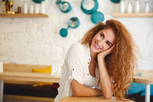 Vacker rödhårig ung dam sitter i café medan poserar. — Stockfoto