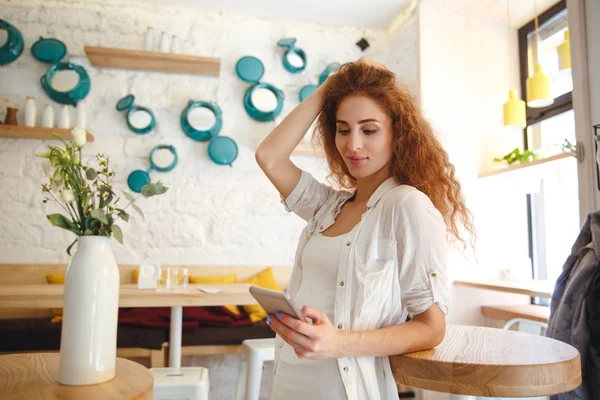 Bella rossa giovane signora in piedi in caffè mentre chatta — Foto Stock