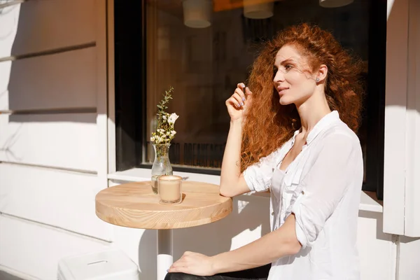 Portré, fiatal, gyönyörű vörös hajú nő ül egy kávézóban — Stock Fotó