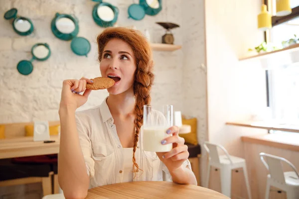 Mujer desayunando con galletas y leche en la mesa — Foto de Stock