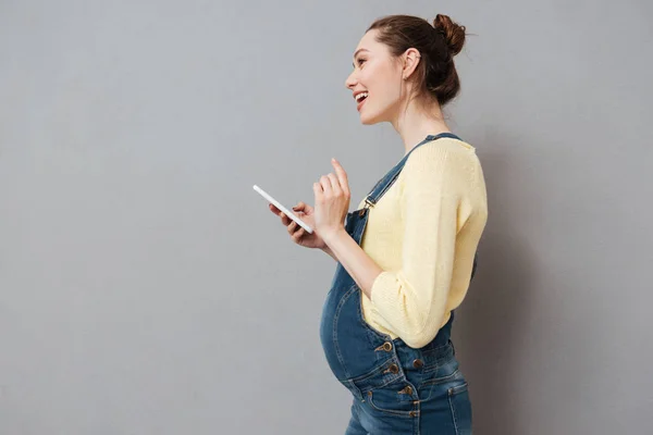 Vista lateral de una joven embarazada sosteniendo teléfono móvil — Foto de Stock