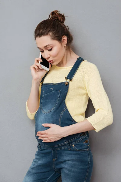 Porträtt av en ung casual gravid kvinna med mobiltelefon — Stockfoto