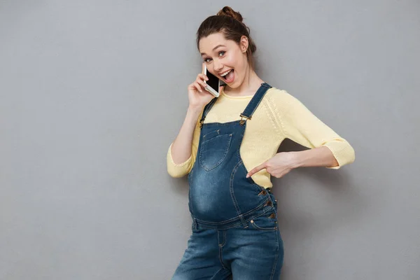 Gladlynt upphetsad gravid kvinna som står och pratar i mobiltelefon — Stockfoto