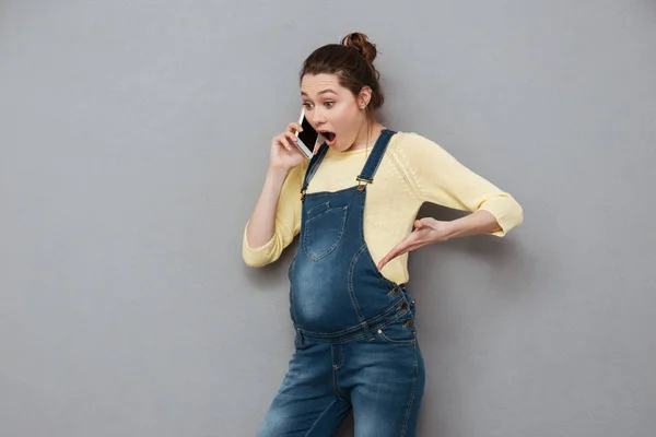Meglepett döbbenve terhes nő állt, és beszélt a mobiltelefon — Stock Fotó