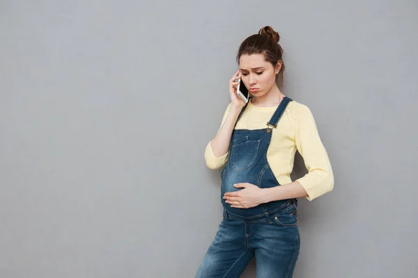 Cep telefonu üzerinde konuşurken endişeli genç hamile kadın — Stok fotoğraf
