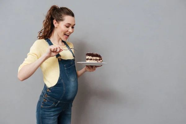 Çikolatalı kek yeme bir heyecanlı genç hamile kadın portresi — Stok fotoğraf
