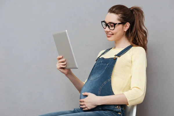Mulher feliz grávida usando computador tablet . — Fotografia de Stock