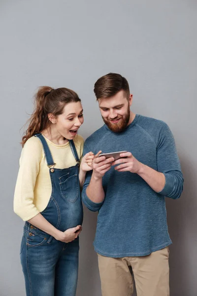 Портрет счастливой улыбающейся молодой пары с помощью мобильного телефона — стоковое фото