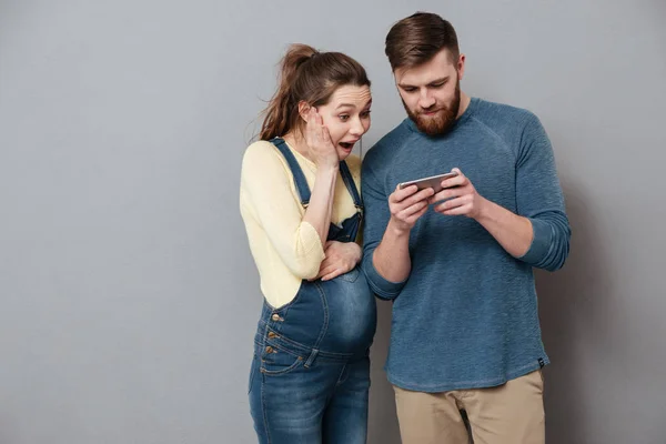 Unga spännande par tittar tillsammans på mobiltelefon isolerade — Stockfoto