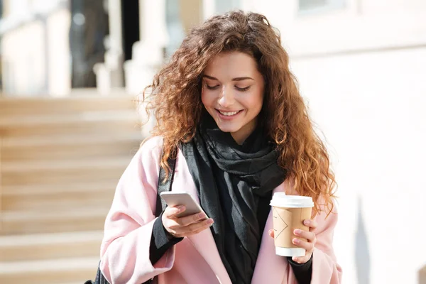 Retrato de una linda mujer joven usando el teléfono celular en la calle . — Foto de Stock