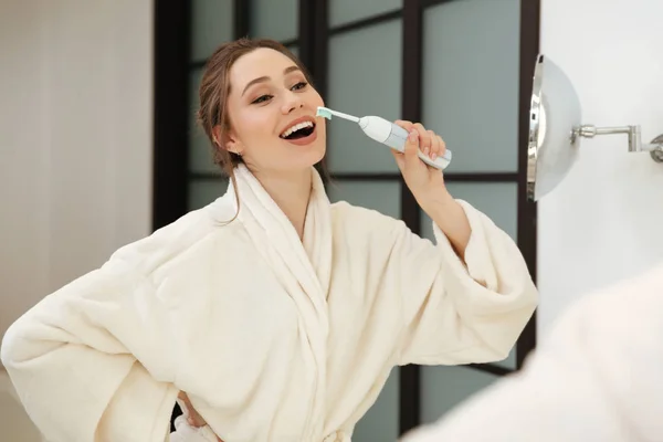 Vrolijke mooie jonge vrouw haar tandenpoetsen in de badkamer — Stockfoto