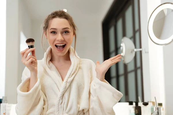 Ευτυχισμένη γυναίκα εφαρμογή πινέλο πούδρας και κάνω μακιγιάζ στο μπάνιο — Φωτογραφία Αρχείου