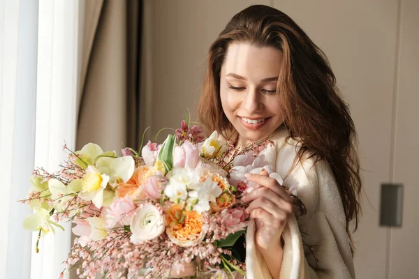 Mulher sorridente com buquê de flores em casa — Fotografia de Stock