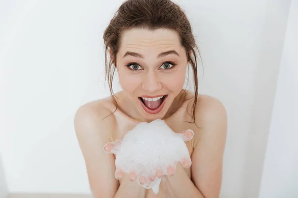 Happy woman sitting in bathtub with foam and having fun — Stock Photo, Image