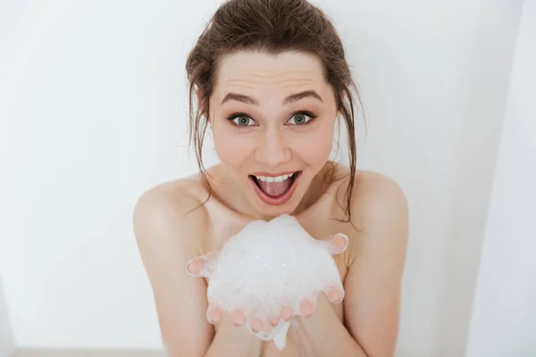 Mulher feliz sentada na banheira com espuma e se divertindo — Fotografia de Stock