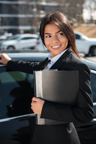 Весела бізнес-леді з текою біля чорного автомобіля — стокове фото