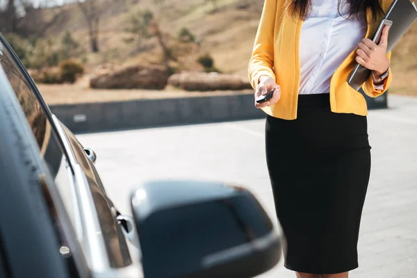 Geschäftsfrau in gelber Jacke schließt die Tür ihres Autos — Stockfoto