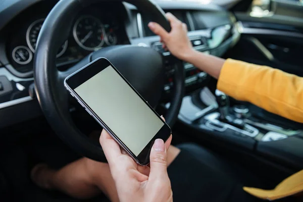 Young woman driver using touch screen smartphone — Stock Photo, Image