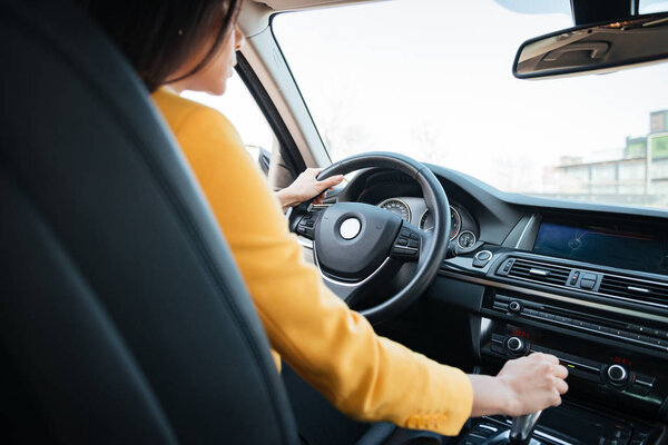 Back view of attractive young woman looking on the road while driving a car