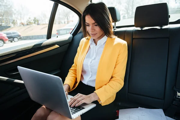 Empresaria sentada en el asiento trasero del coche y trabajando — Foto de Stock