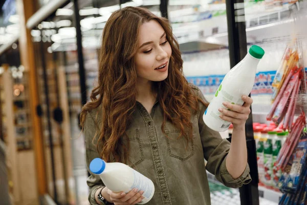 Lächelnde Frau bei der Wahl der Milch — Stockfoto