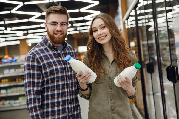 Pareja sonriente eligiendo leche —  Fotos de Stock